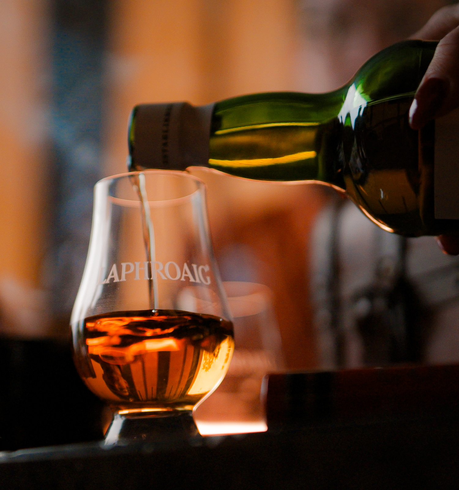 A bottle is pouring a golden liquid into a glass with 