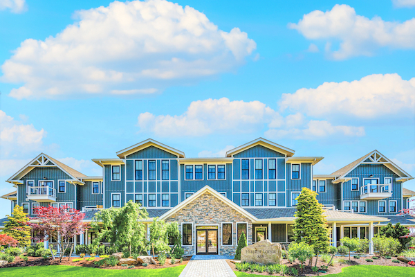 A large, modern building with a manicured lawn and pathway in front, under a bright blue sky with a few clouds ending the sentence.