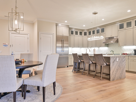 A spacious kitchen with a central island, modern chairs, and hanging light fixtures in a luxury residence at The Preserve Sporting Club & Resort.