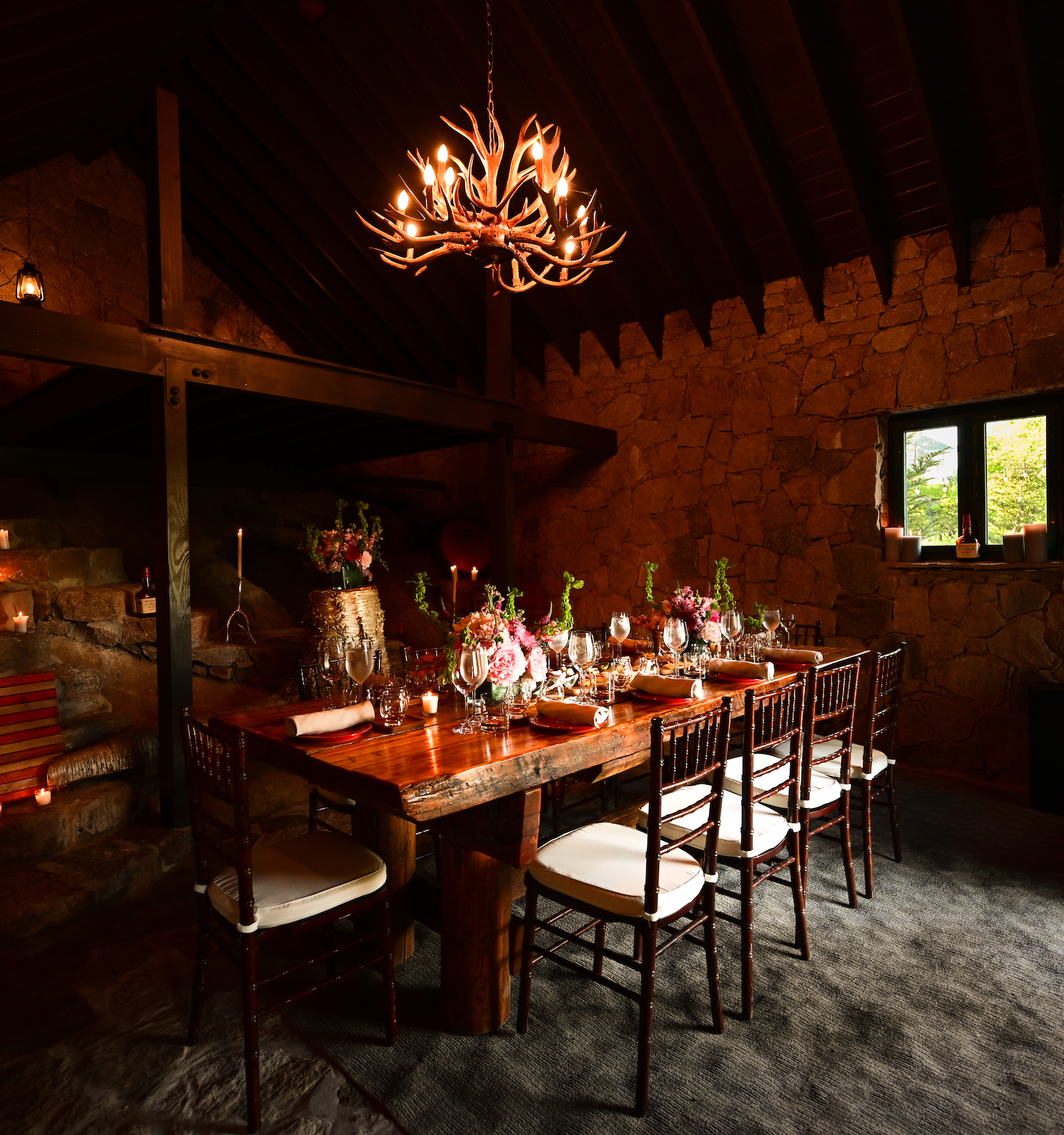 A rustic dining room features a wooden table set with flowers, a chandelier, a sunflower decoration, and a cozy, warm ambiance.