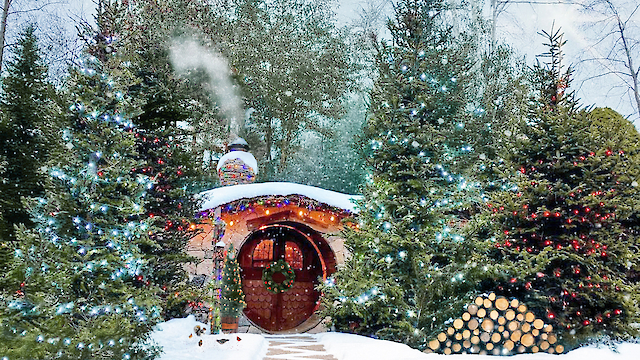 A cozy, snow-covered house in a forest with decorative lights and smoke from the chimney, surrounded by snowy trees and a woodpile.