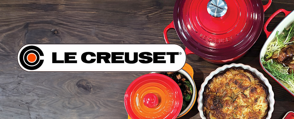 This image shows Le Creuset cookware, including pots and a casserole, alongside the Le Creuset logo on a wooden surface.